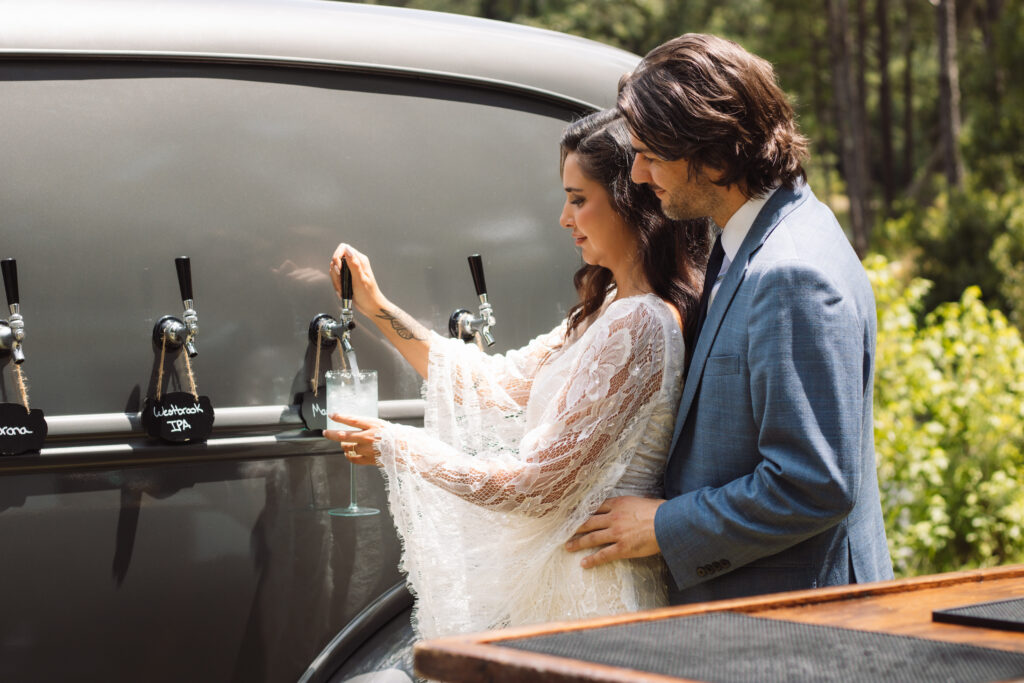 Bride and groom enjoying cocktails from a Lowcountry Taps vintage mobile bar at an outdoor wedding.